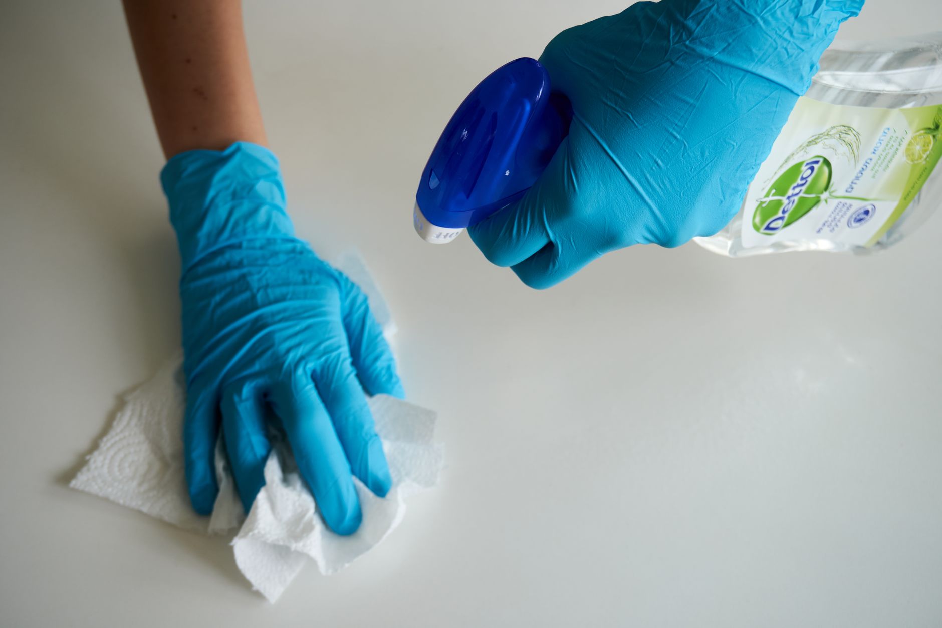Gloved hands cleaning and disinfecting a surface