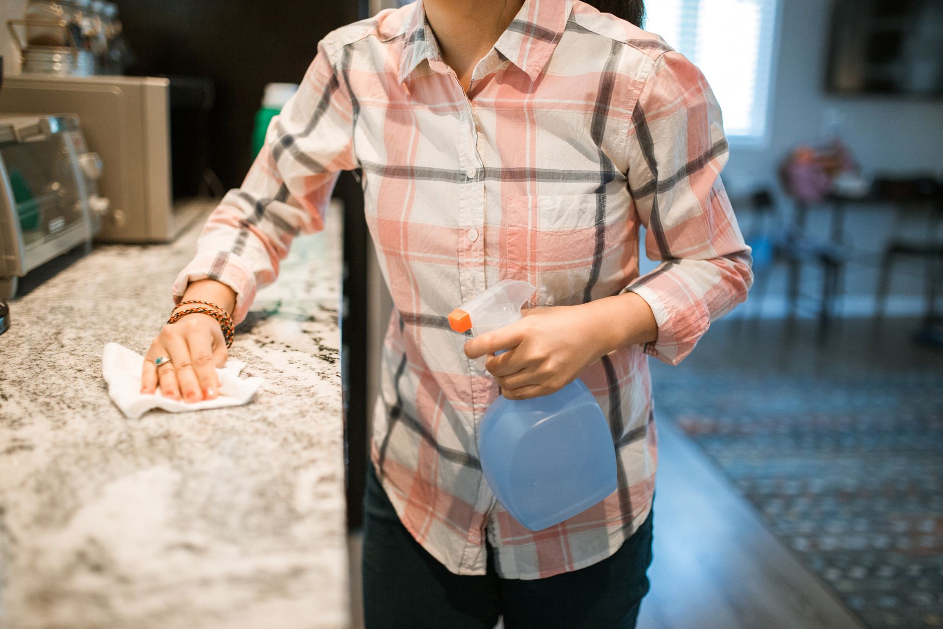 A professional cleaning a kitchen counter with spray and cloth