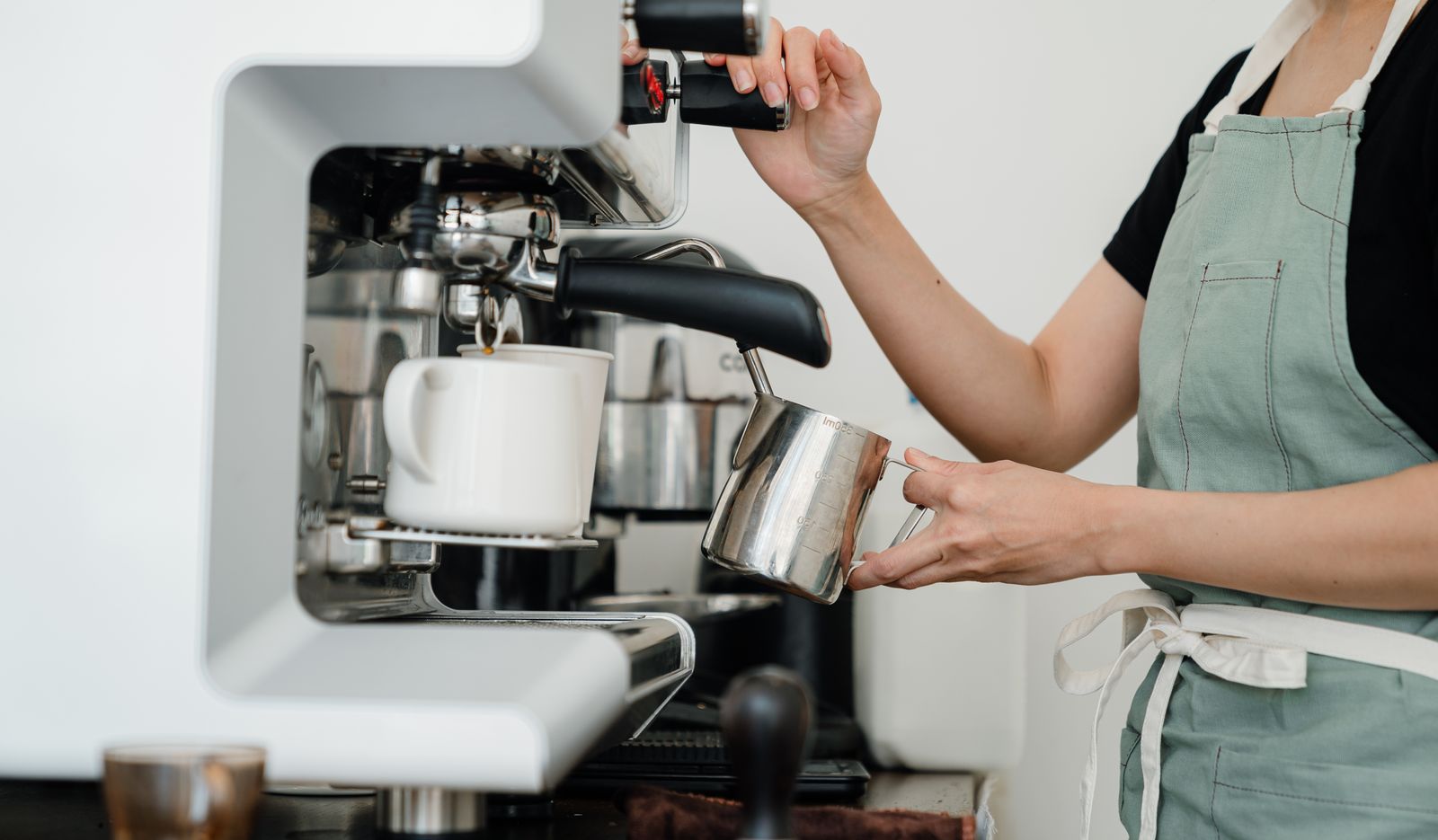 A barista steaming milk at an espresso machine