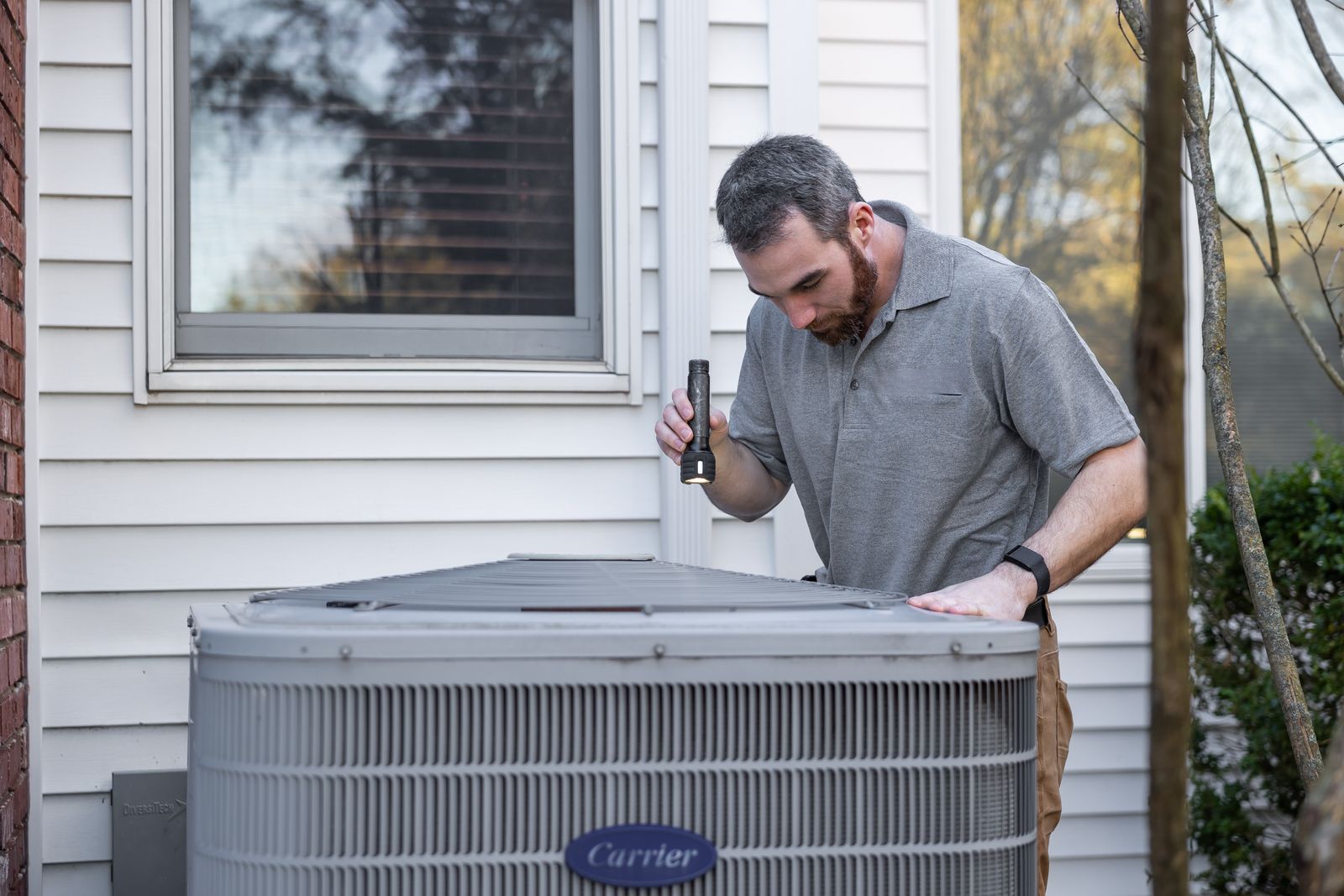 An HVAC technician inspecting an outdoor unit