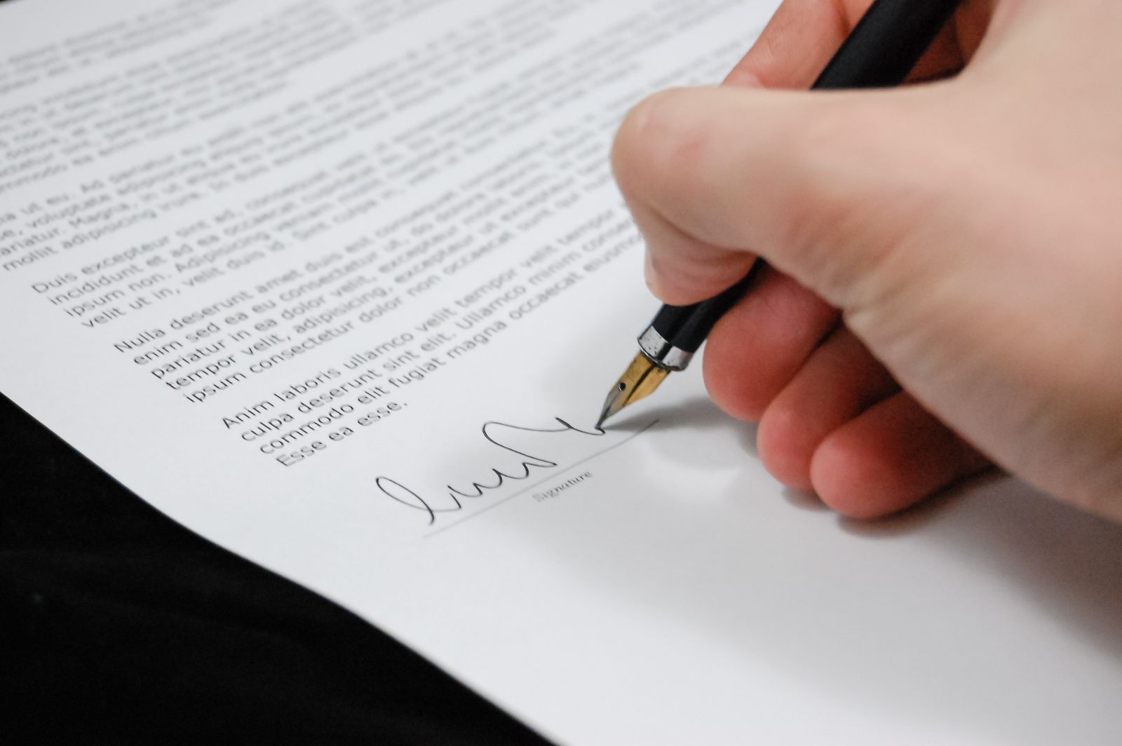 A hand signing a legal immigration document