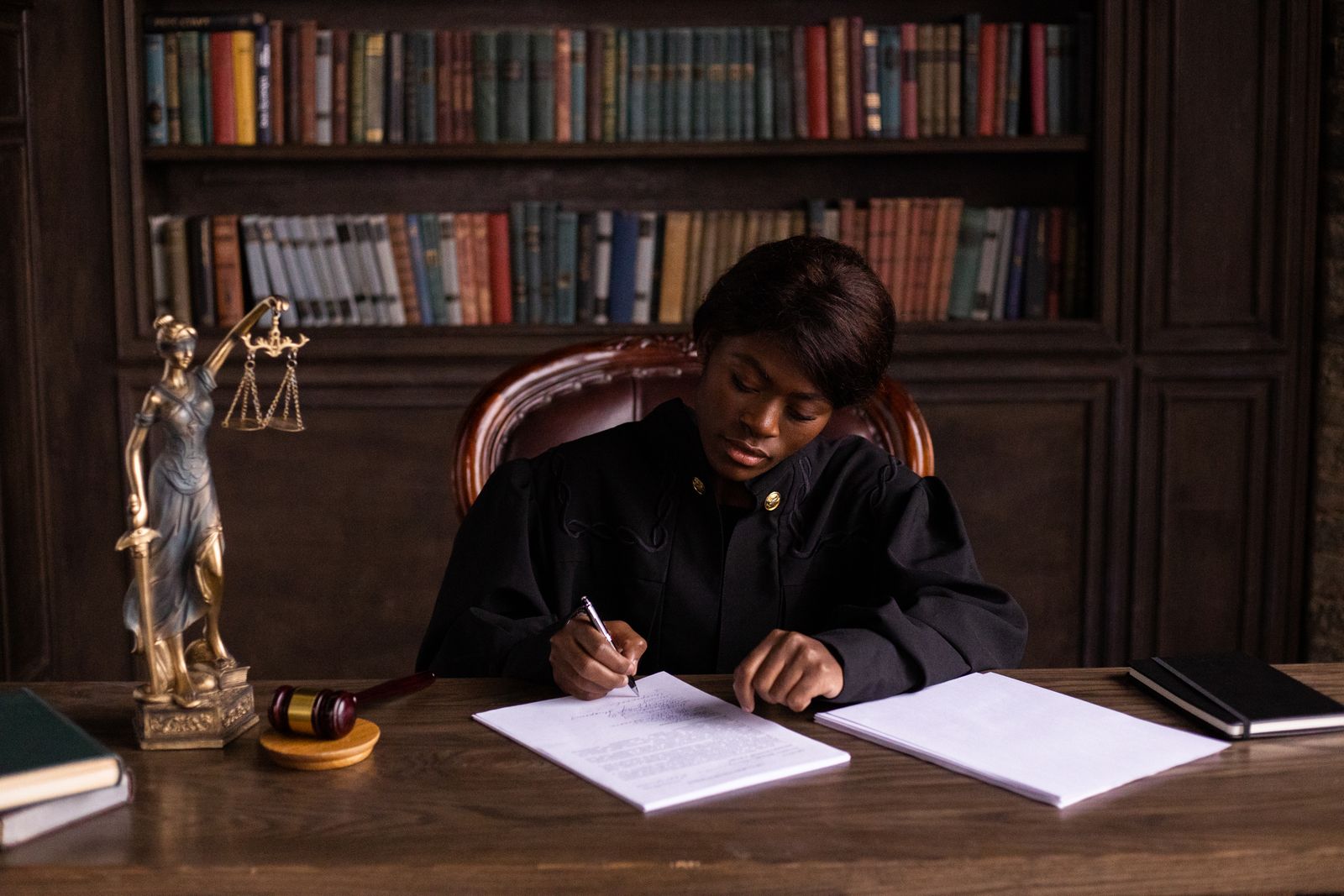 A judge writing on a document at a desk