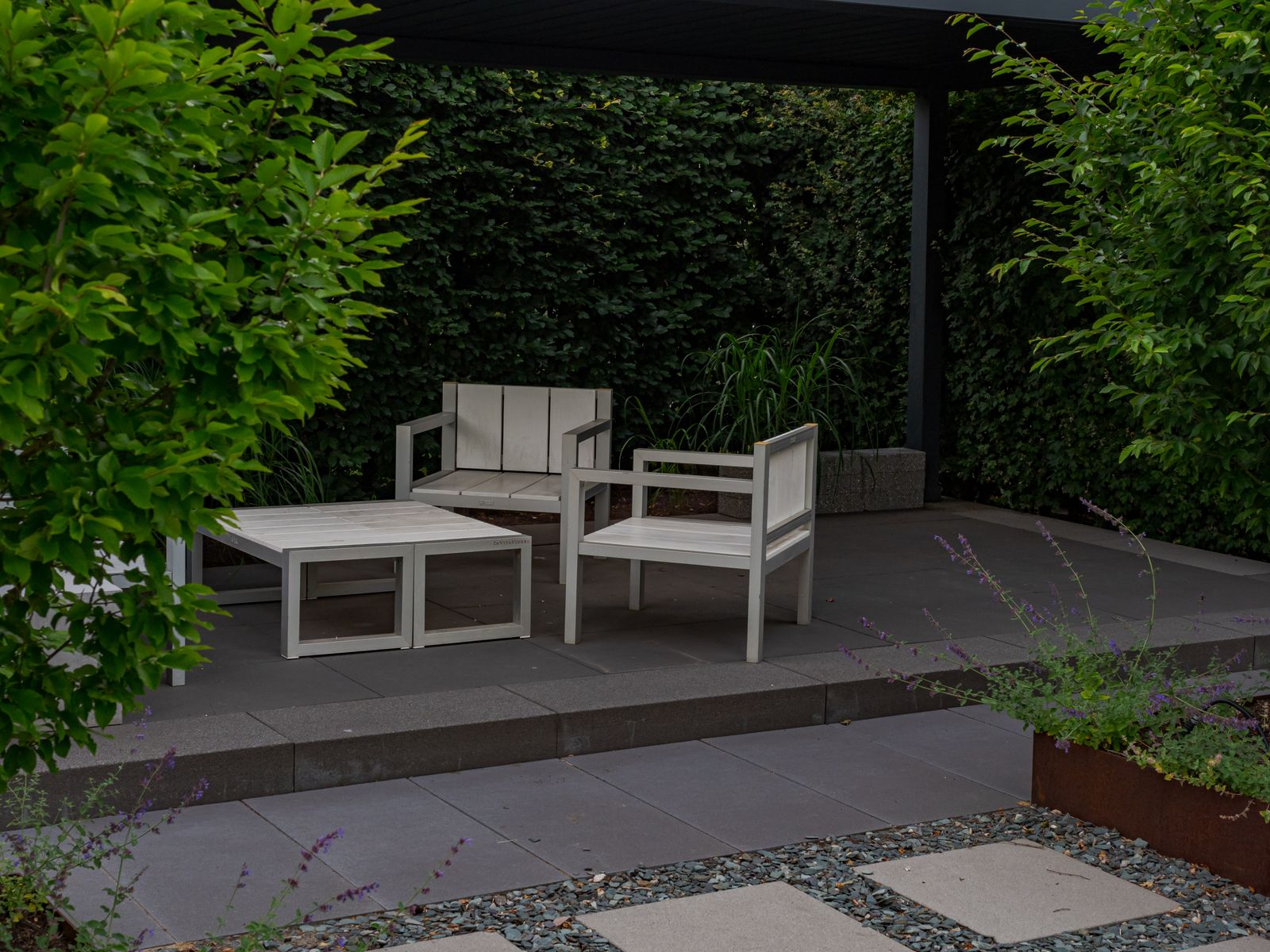 A modern landscaped backyard patio with plants and outdoor furniture