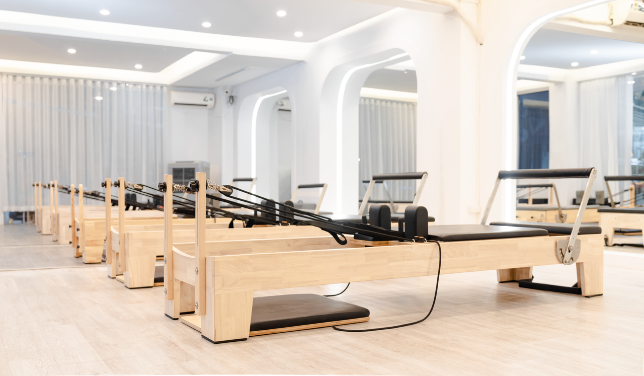 A minimalist Pilates studio with wooden reformers