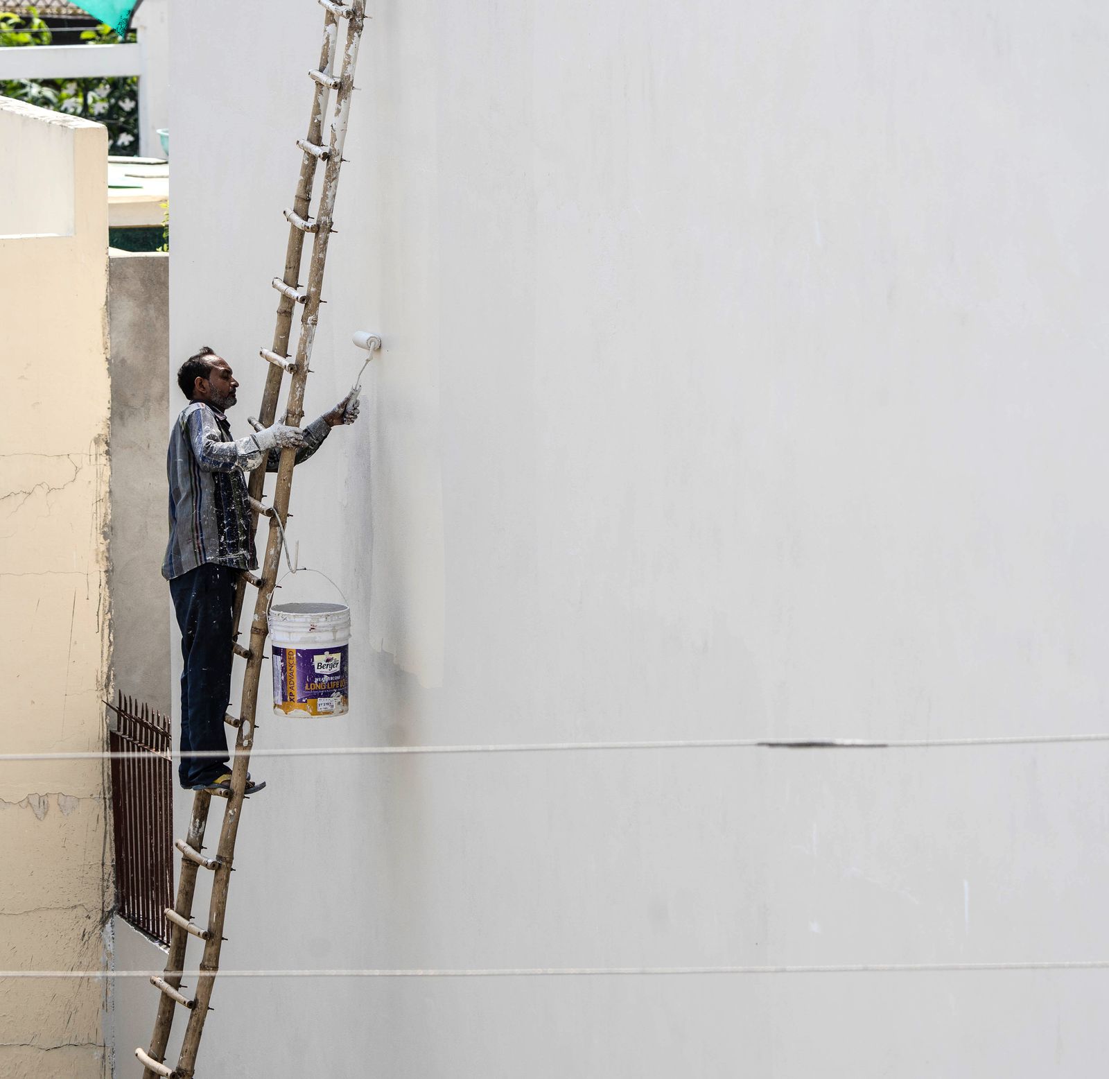 A painter on a ladder painting a building exterior
