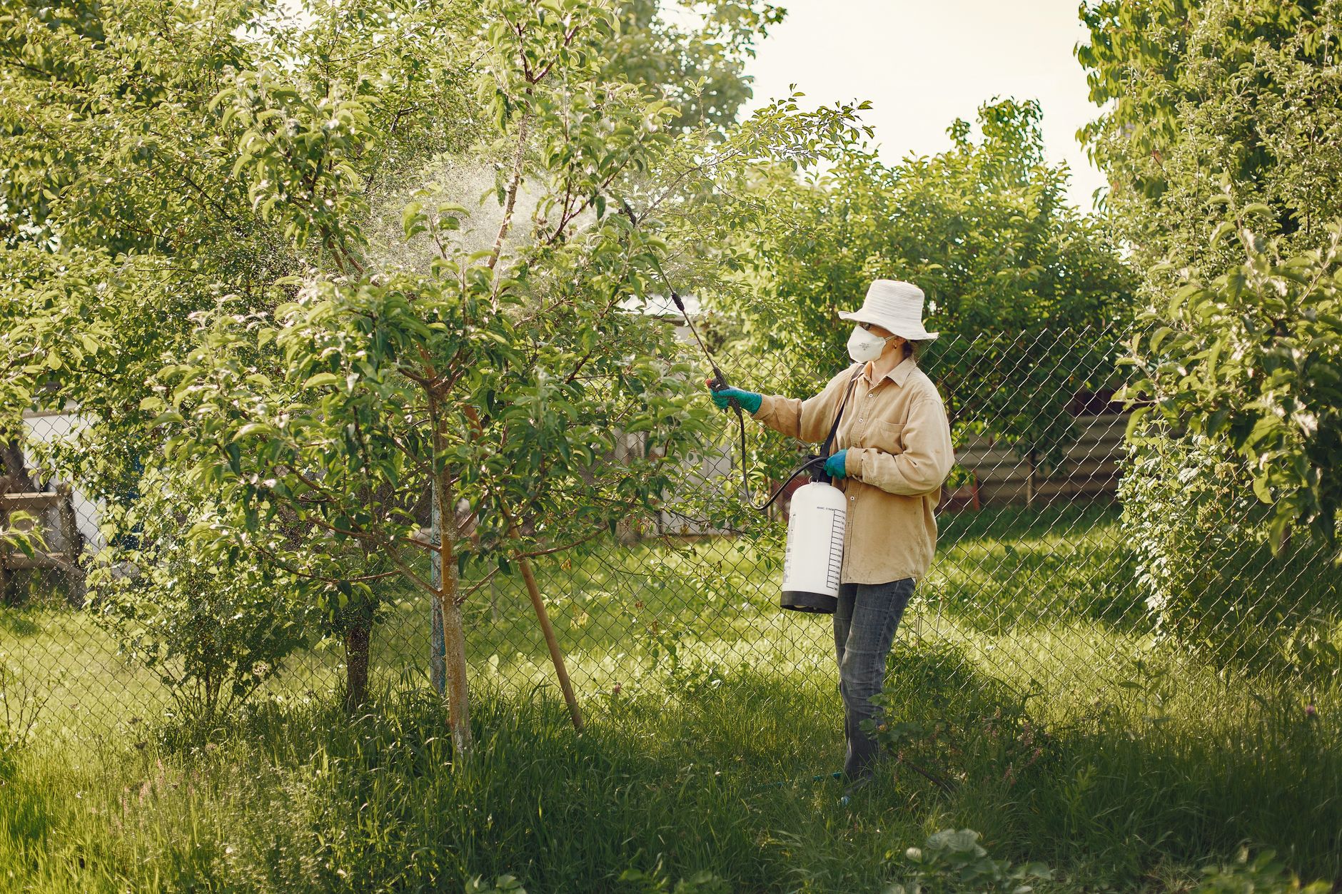 A pest control technician in protective gear spraying treatment