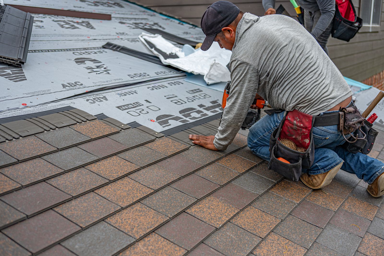 A roofer installing asphalt shingles